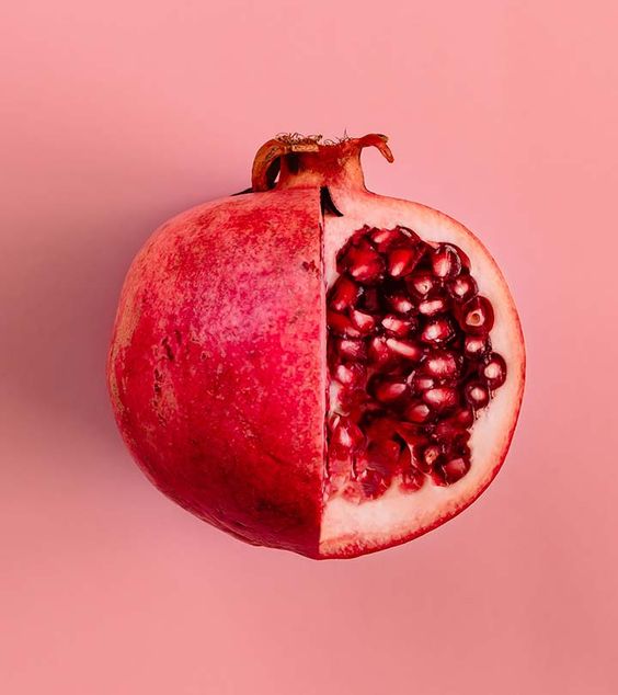 Pomegranate cut in half on a pink background